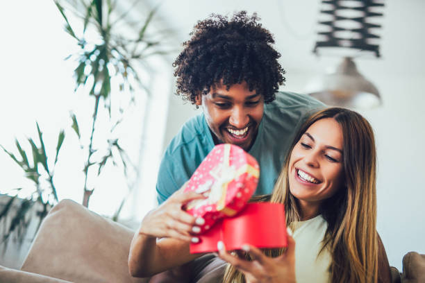 istock Smiling man surprises his girlfriend with present at home. 1224371071