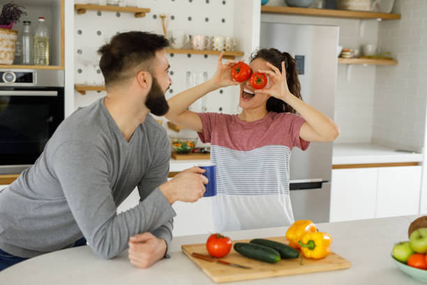 istock Playful couple preparing salad in a domestic kitchen 1224371736