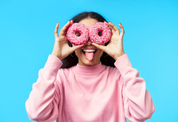 istock Attractive black woman having fun with donuts on blue background 1224372695
