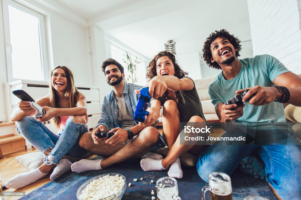Group of friends having fun playing video games at home. Happy group of young friends playing video games at home. Friendship Stock Photo