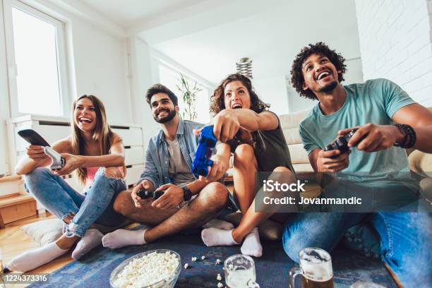 Group Of Friends Having Fun Playing Video Games At Home Stock Photo - Download Image Now