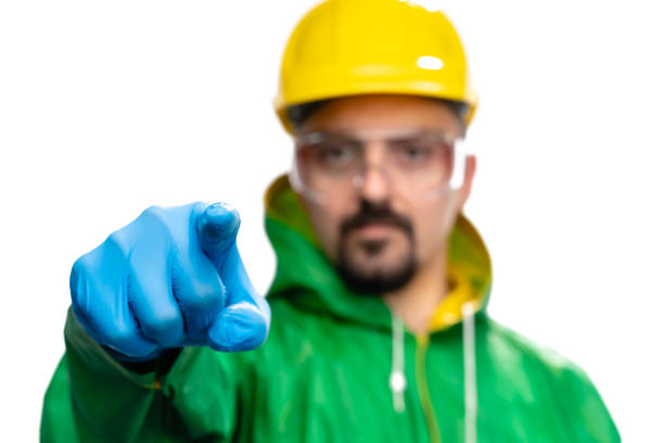 Young engineer or worker with safety equipment pointing at camera on white background, close-up. Photo is taken in studio environment with Sony A7III camera
