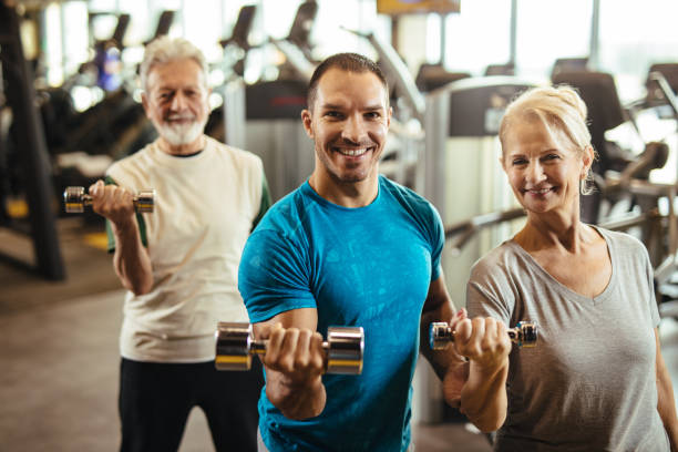 istock Senior couple exercising with personal trainer using dumbbells at the gym 1224374788