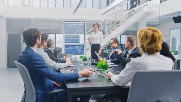 istock In the Corporate Meeting Room: Female Analyst Uses Digital Interactive Whiteboard for Presentation to a Board of Executives, Lawyers, Investors. Screen Shows Company Growth Data with Graphs 1224381178