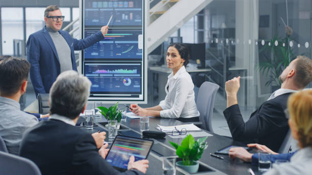 istock In the Corporate Meeting Room: Creative Director Uses Digital Interactive Whiteboard for Presentation to a Board of Executives, Lawyers, Investors. Screen Shows Company Growth Data with Digital Graph 1224381184