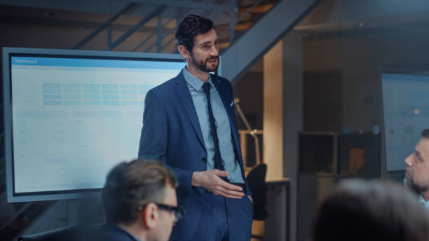 istock In Corporate Meeting Room: Energetic and Young Startup Creator Uses Digital Interactive Whiteboard for Presentation and Delivers Powerful Speech to a Board of Executives Investors and Businesspeople 1224381314
