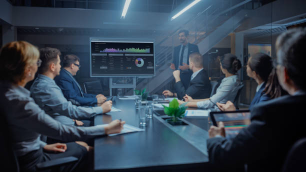 istock In the Corporate Meeting Room: Male Executive Talks and Uses Digital Interactive Whiteboard for Presentation to a Board of Directors, Investors. Screen Shows Growth Data. Late at Night Office 1224381465