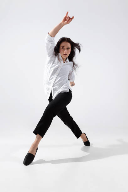 白いスタジオの背景に隔離された最小限の黒いスタイルの若くて優雅なバレエダンサー - jumping business women dancing ストックフォトと画像