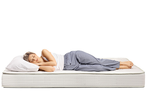 Young woman in pajamas sleeping on a comfortable mattress isolated on white background