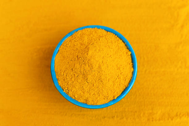 istock Top view turmeric powder in blue bowl at orange background. 1224387513