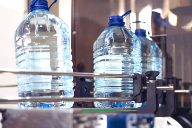 istock Bottling plant - Water bottling line for processing and bottling pure spring water into blue bottles. Selective focus. 1224388295