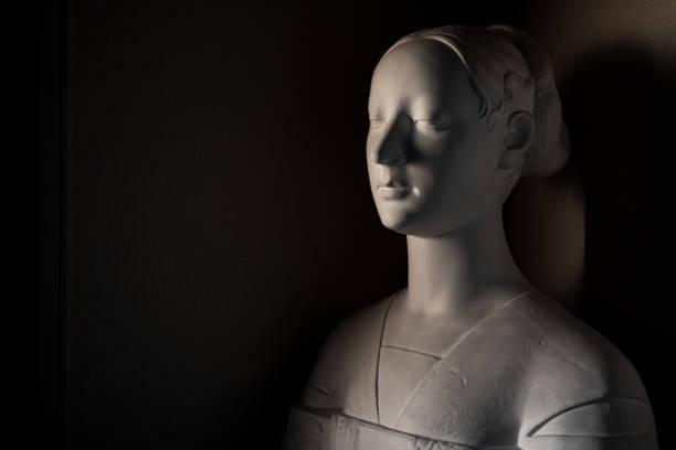 An angry Buddah face is composed in the right portion of the frame in shadow, and showing only the left half of the face. The focus is on the left eye. In the background, a second Buddah face can be seen smiling and looking toward the light source