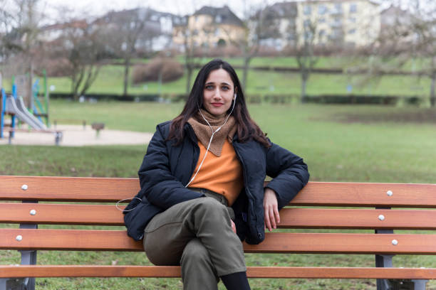 istock Young Woman Sitting on Bench Looking Towards the Camera with Confidence 1224392984