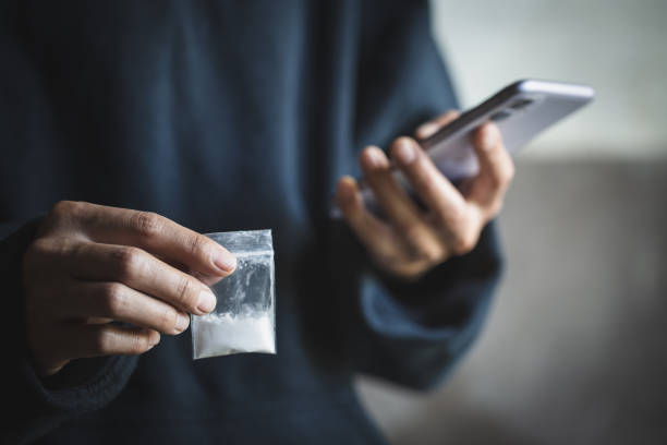 drogendealer nutzen das telefon, um den kunden zu kontaktieren, drogenhandel, kriminalität, sucht und verkauf, das konzept des kaufs und verkaufs von drogen. - drug dealer stock-fotos und bilder