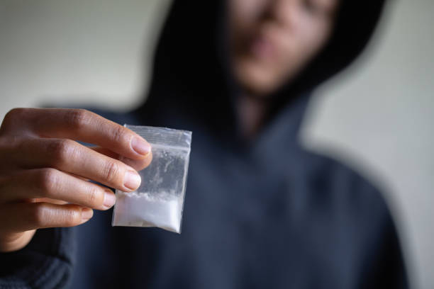 コカインやヒロインを保持している中毒者の手、麻薬販売業者からの中毒購入用量のクローズアップ、麻薬密売、犯罪、中毒と販売の概念、 - narcotic ストックフォトと画像