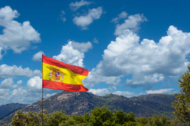 winken spanische flagge in einem berg hintergrund - spain flag built structure cloud stock-fotos und bilder