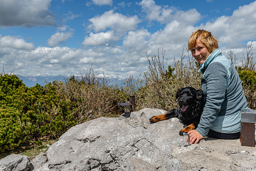 Happy Senior Woman enjoys with a black dog on top of the hill in Julian Alps, Primorska Slovenia, Europe,Nikon D850