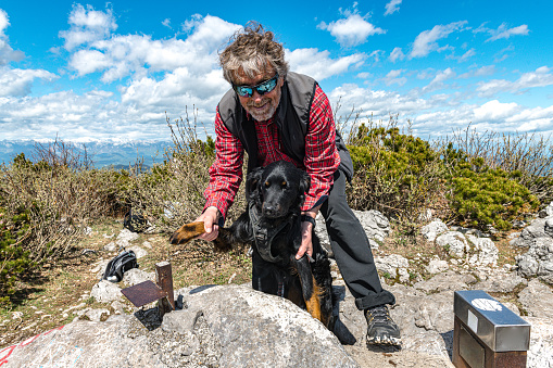 Happy Senior man enjoys with a black dog on top of the hill in Julian Alps, Primorska Slovenia, Europe,Nikon D850