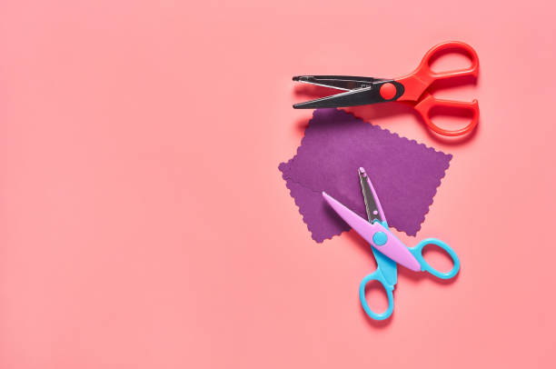 istock Two scissors for decorative curly cutting and blank paper for craft with wave border on pink background. Concept of handmade, leisure or preschool education 1224400471