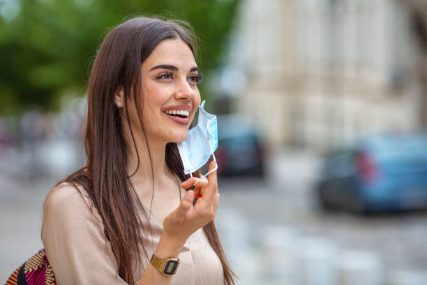 mujer quitándose la máscara al aire libre. - despegar actividad fotografías e imágenes de stock