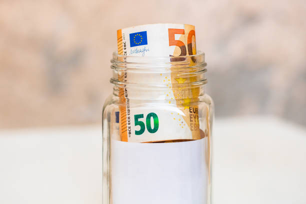 istock Composition with saving money banknotes (50 EURO) in a glass jar with empty white label or note for your text. Concept of investing and keeping money, close up isolated. 1224400944