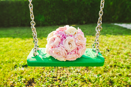 Bride's bouquet with pink colored roses on a green swing