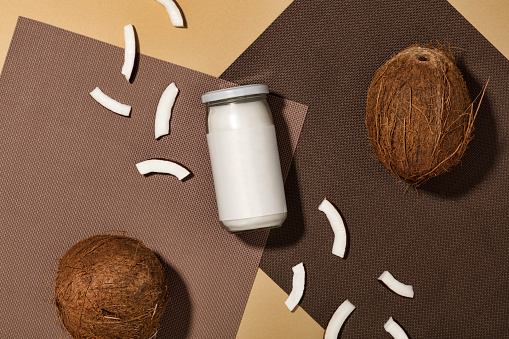 Organic healthy coconut butter and fresh coconut pieces on brown background