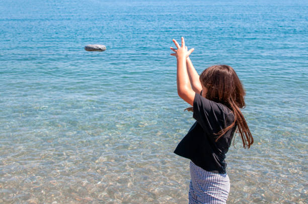 bambina carina che gioca con la roccia sulla spiaggia - throwing stone human hand rock foto e immagini stock