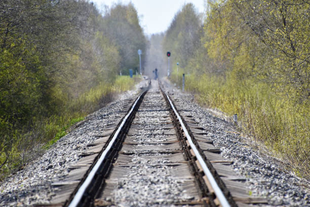 Railroad long shot with a man figure standing in the middle. Hot summer day railroad long shot with a man figure standing in the middle, heat wave distortion. railroad track concrete railway sleeper thoroughfare stock pictures, royalty-free photos & images