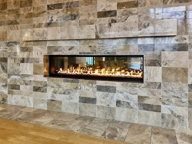 View of  beautiful burning gas fireplace surrounded by updated and modern tile