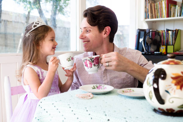 小さな女の子は彼女のお父さんとお茶会を持っています - tea party little girls teapot child ストックフォトと画像