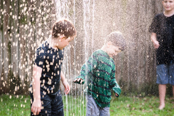 istock Brothers playing in sprinkler 1224406067