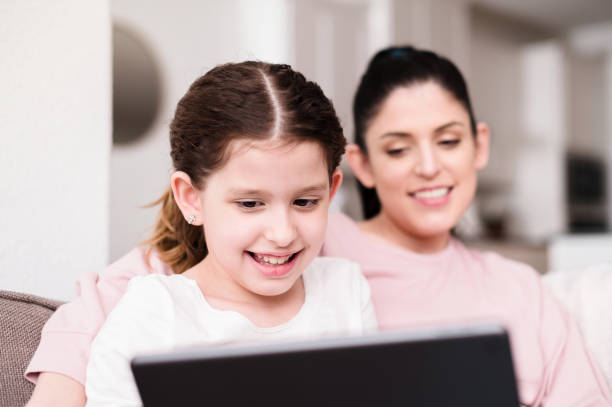 istock Mid adult mother and elementary age daughter video conference 1224406105