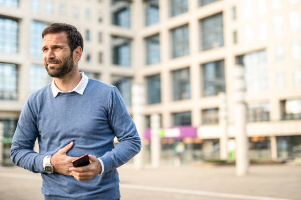 man in the city having stomachache. - stomachache illness pain indigestion imagens e fotografias de stock