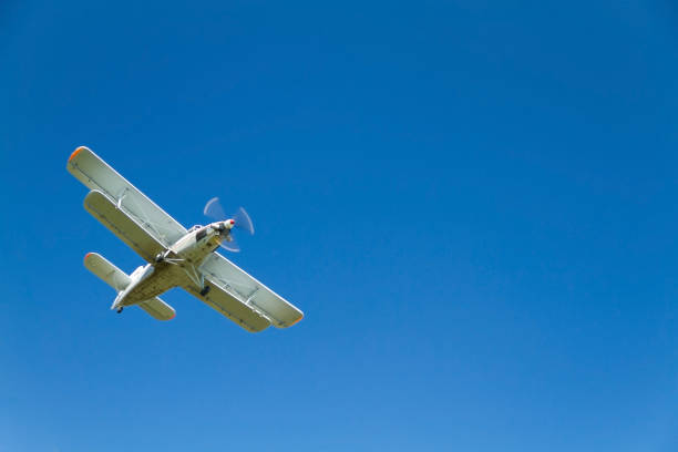 istock Retro airplain - biplane flying the air against a blue sky, with a fast-turning propeller. View from below 1224407069