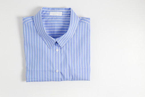 One perfectly folded buttoned shirt with striped pattern. Single piece of formal wear with blank label isolated on white background. Close up, top view, copy space.