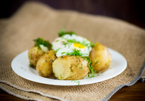 boiled early potatoes with fried egg and dill in a plate