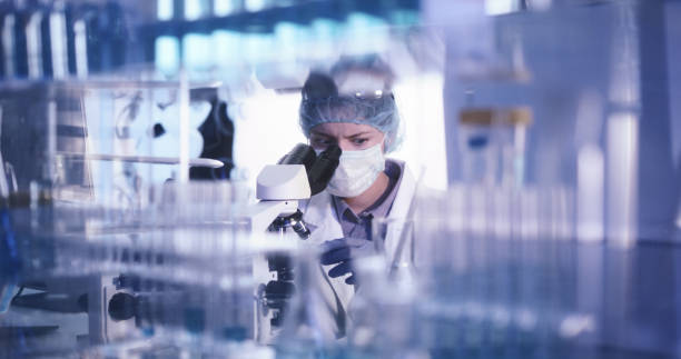 istock Young female microbiologist studying coronavirus - protective workwear 1224413551