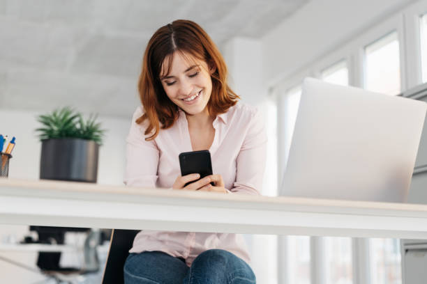 istock Young woman smiling at a message on her mobile 1224413560