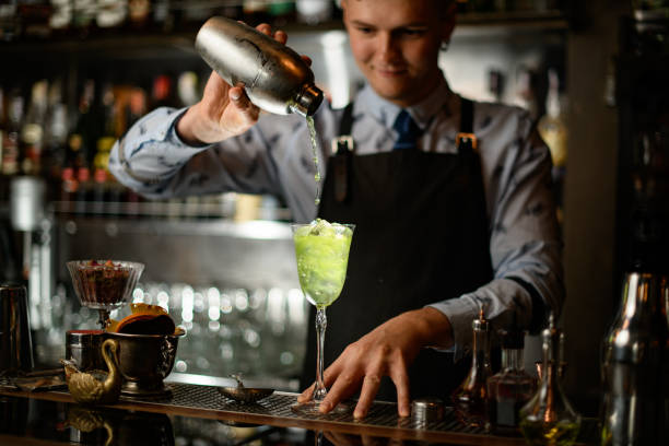 istock man at bar pours cocktail from shaker into glass. 1224413771