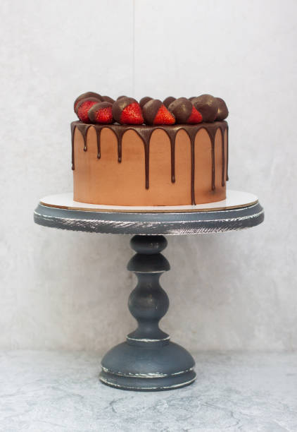 istock Chocolate brownie cake with strawberries dipped into melted chocolate. Grey cakestand, grey background. Copy space. 1224421544