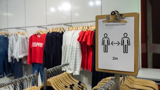 Munich, Bavaria / Germany - May 5, 2020: Keep distance sign inside an Esprit store. Clothes in the background. The fashion retailer initiated a protective shield proceeding to survive the crisis.