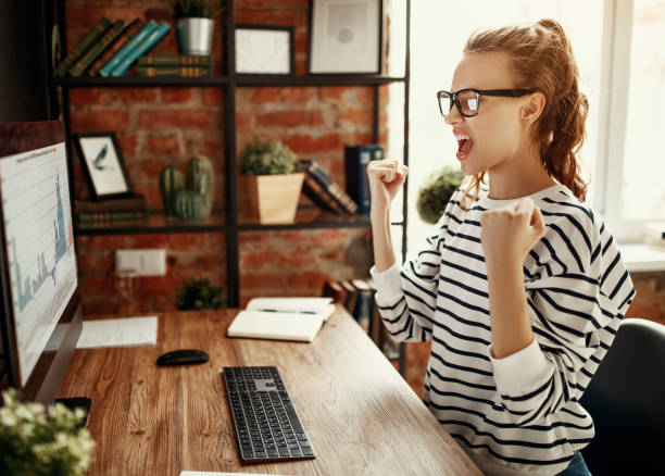 istock Excited woman celebrating victory while working at computer in loft office 1224422553