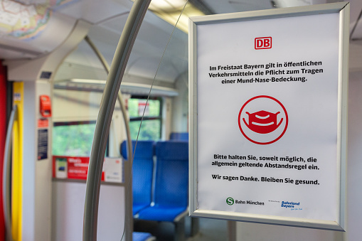 Munich, Bavaria / Germany - May 5, 2020: Sign inside a public transport train (S-Bahn) asking passengers to wear a face mask & to keep distance. Measure in the fight against the Coronavirus (Covid-19)