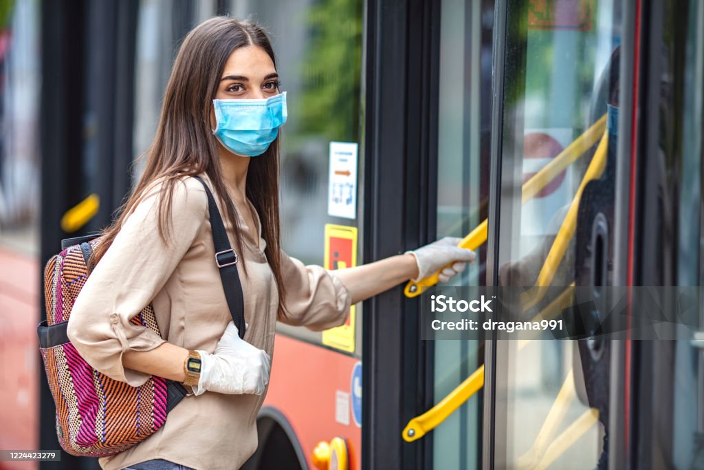 Virus protection in public transportation. Virus pandemic and pollution concept. Woman getting on the bus. Virus protection in public transportation. Woman wearing surgical protective mask going to work Bus Stock Photo