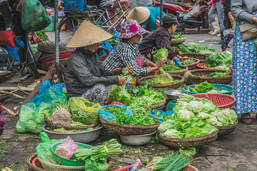 Asian chinese senior man shop owner of the spice store receiving basket of products from his customer for price calculation at the spice stall