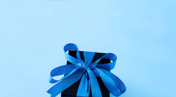 Black gift box on a blue background. Fathers Day concept. Close-up
