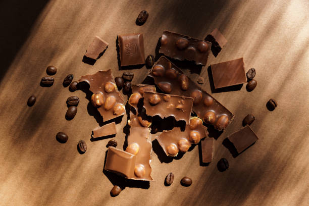 fermez-vous vers le haut du chocolat au lait avec des noisettes sur le fond brun. dessert sucré. - brown chocolate candy bar close up photos et images de collection
