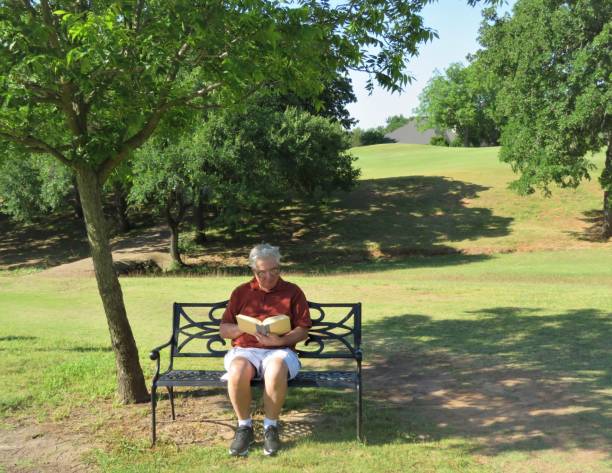 istock Senior Man Reading on Park Bench 1224428456