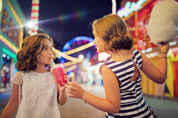 Two little girls are having fun at a amusement park Two little girls are having fun at a amusement park child cotton candy stock pictures, royalty-free photos & images